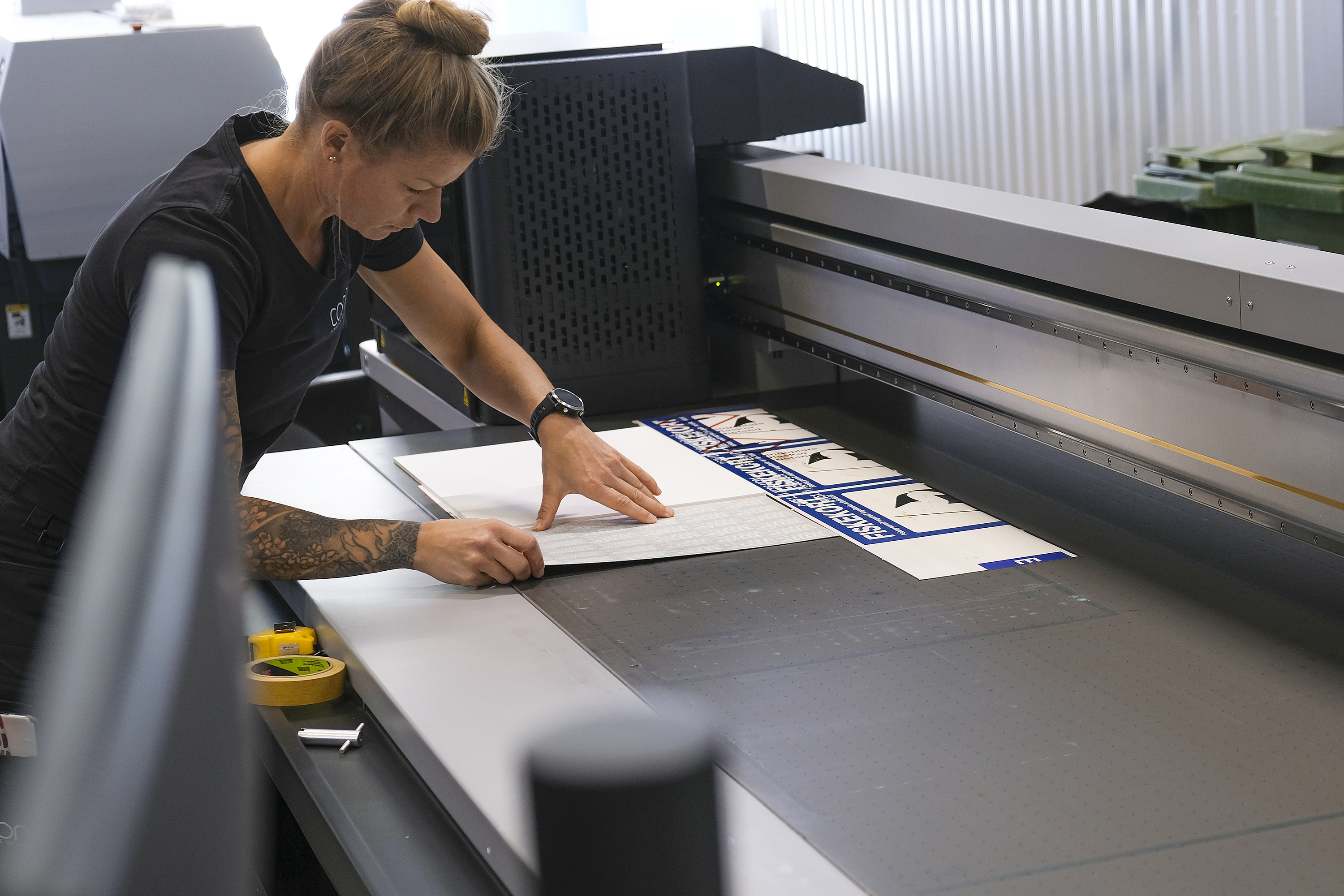 Bild på Skyltmakaren Sara Arvén som förbereder en produktion i en av Concils planprintrar. Bordet har ett antal olika vakuumzoner som stabiliserar skyltämnet.