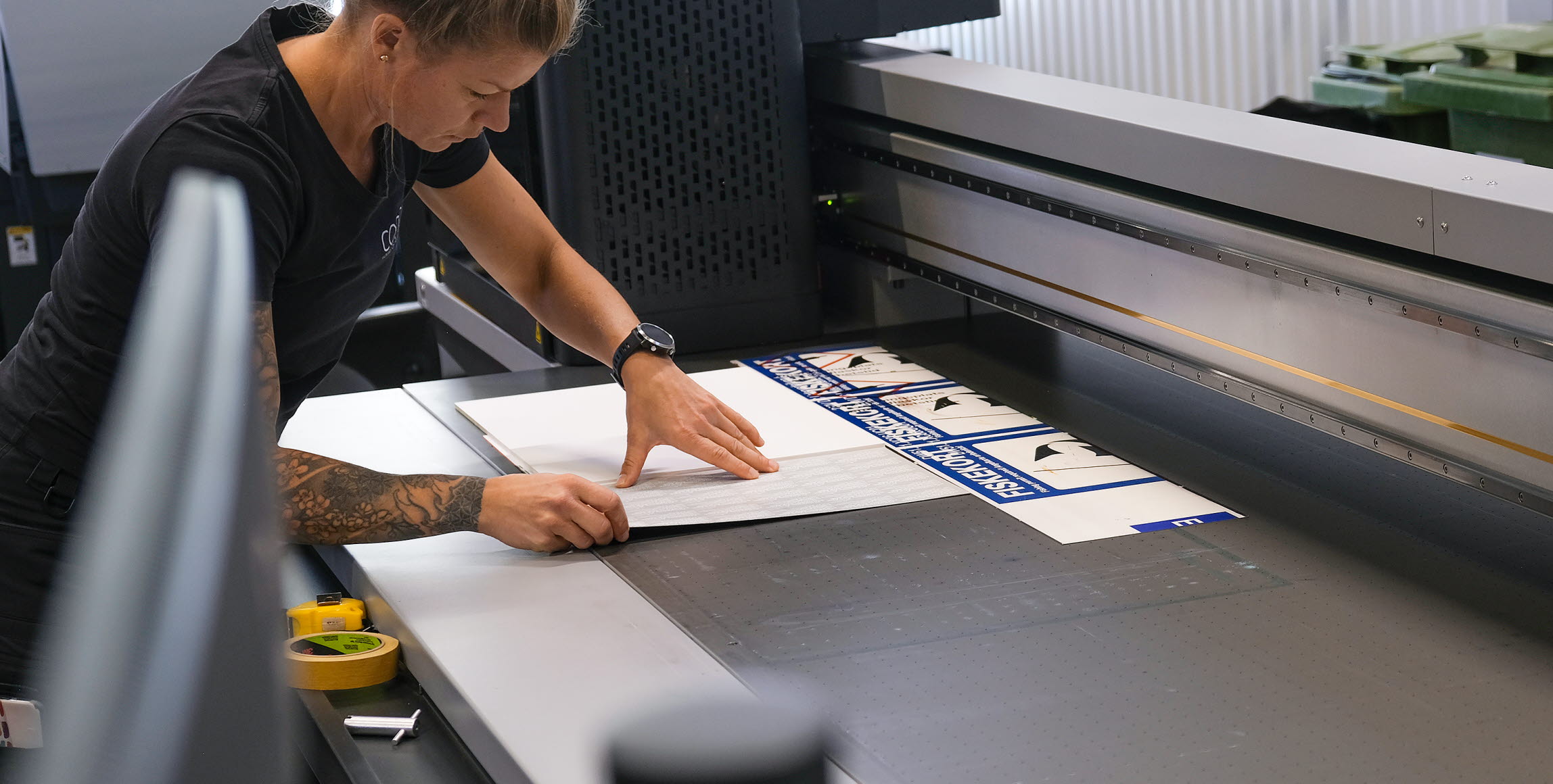 Bild på Skyltmakaren Sara Arvén som förbereder en produktion i en av Concils planprintrar. Bordet har ett antal olika vakuumzoner som stabiliserar skyltämnet.