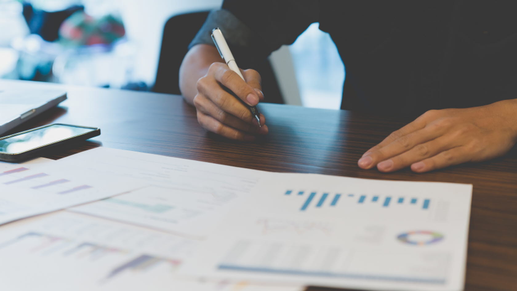 Bild på person med utskrivna papper framför sig med olika typer av grafer och diagram.