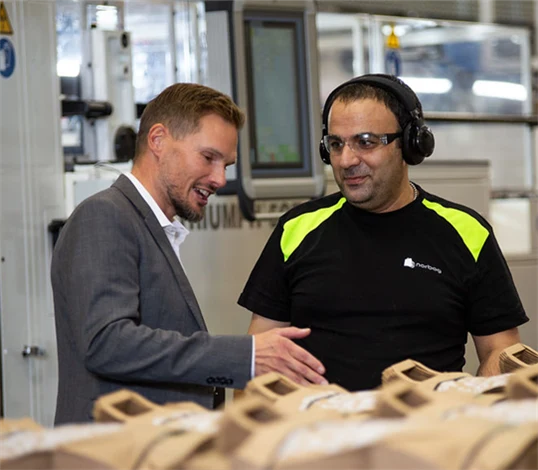 Bild på Torbjörn Rodhe, vd, i samtal med maskinoperatören Issam Ibrahim i Töcksfors.