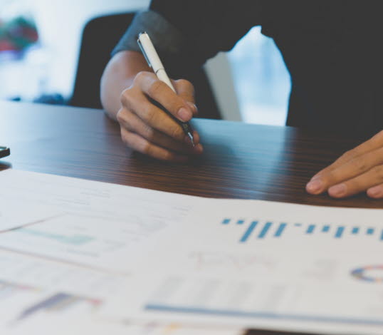 Bild på person med utskrivna papper framför sig med olika typer av grafer och diagram.